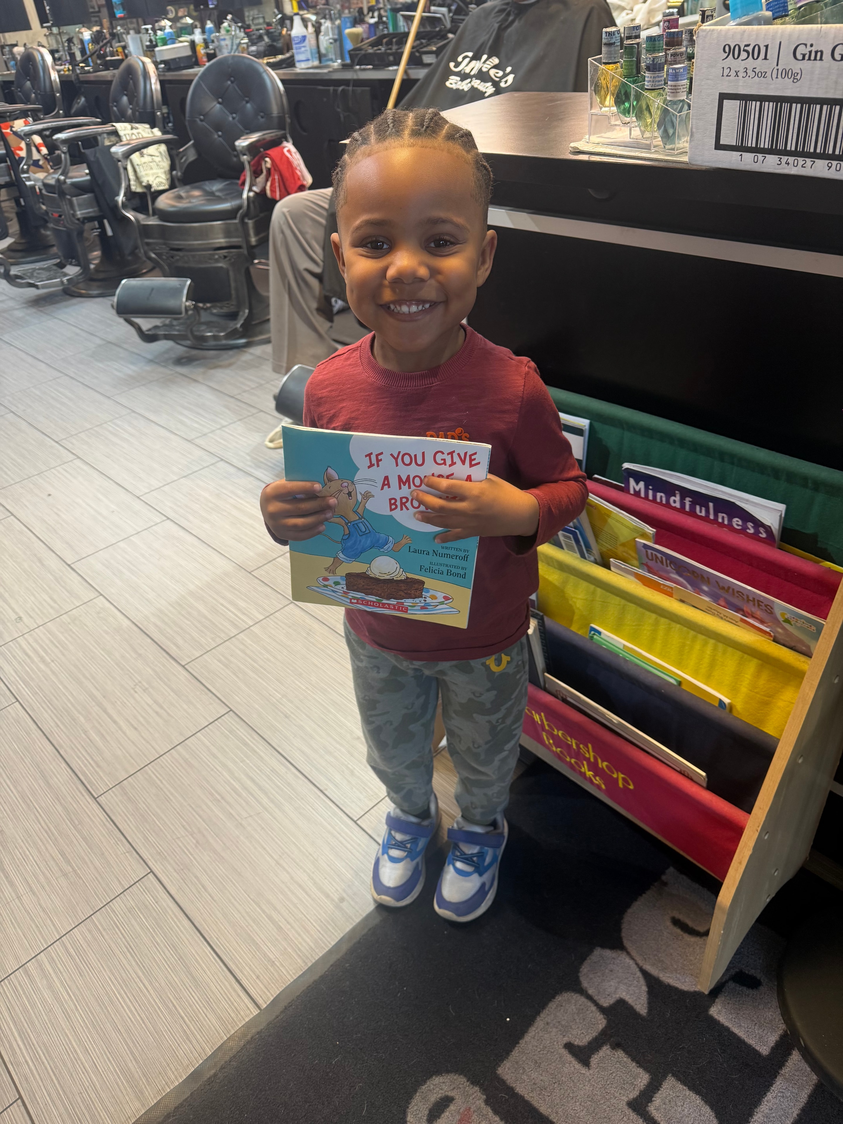Young customer enjoying the book corner at Tommie's Barber-Beauty